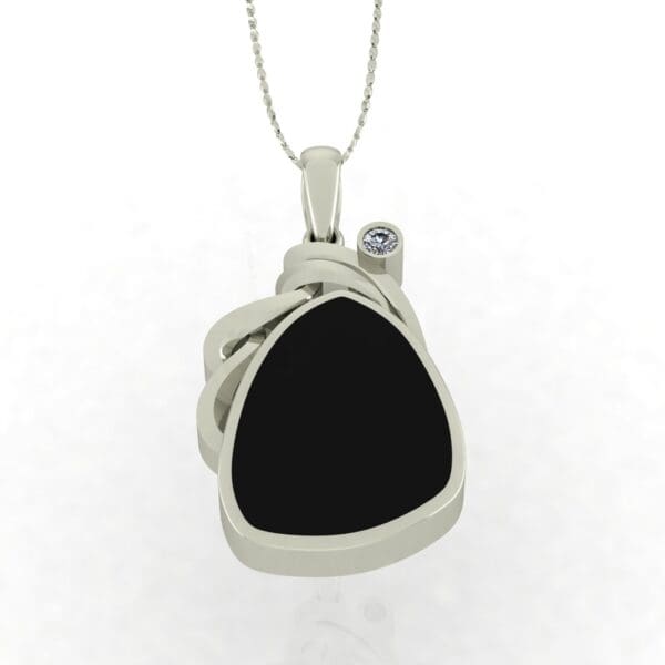 A silver necklace with a black stone and a diamond.