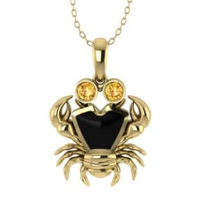 A gold necklace with a crab pendant and two yellow sapphires.
