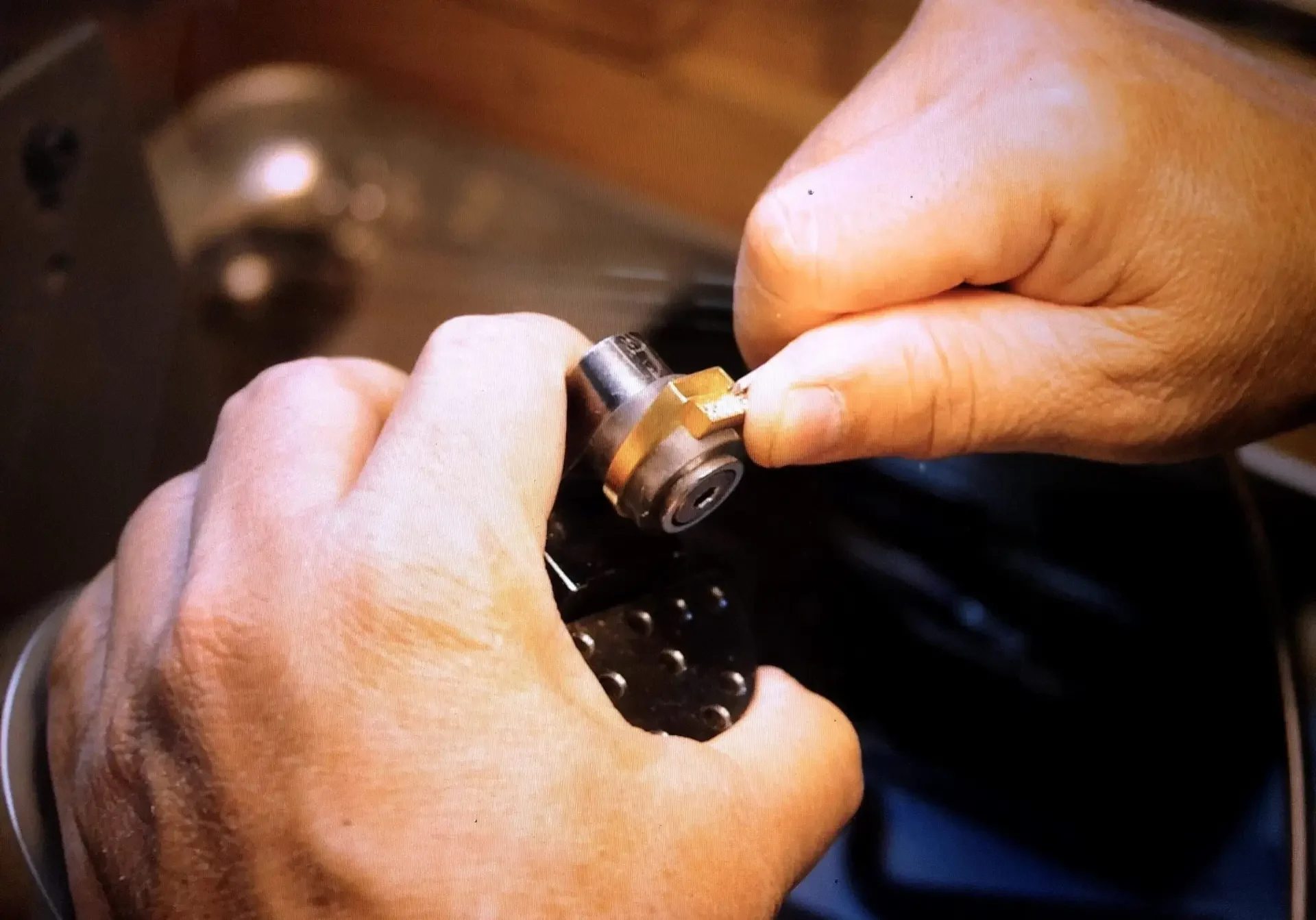 Hands working with small mechanical part.